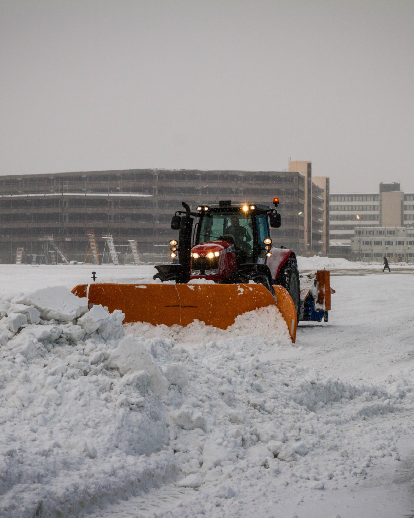 Großer Traktor mit Schneepflug beim Schneeräumen